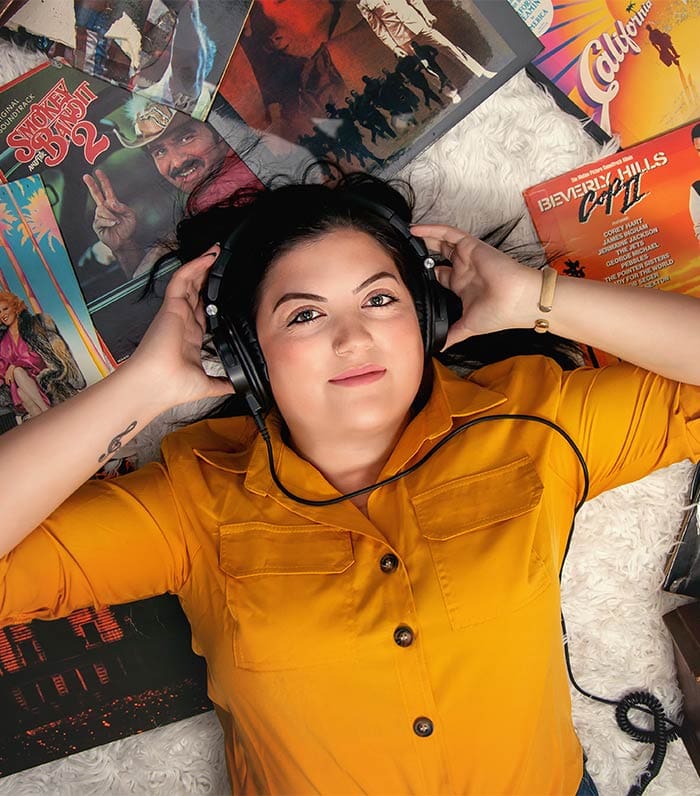 Mariah Land laying on album covers listening to WHFB